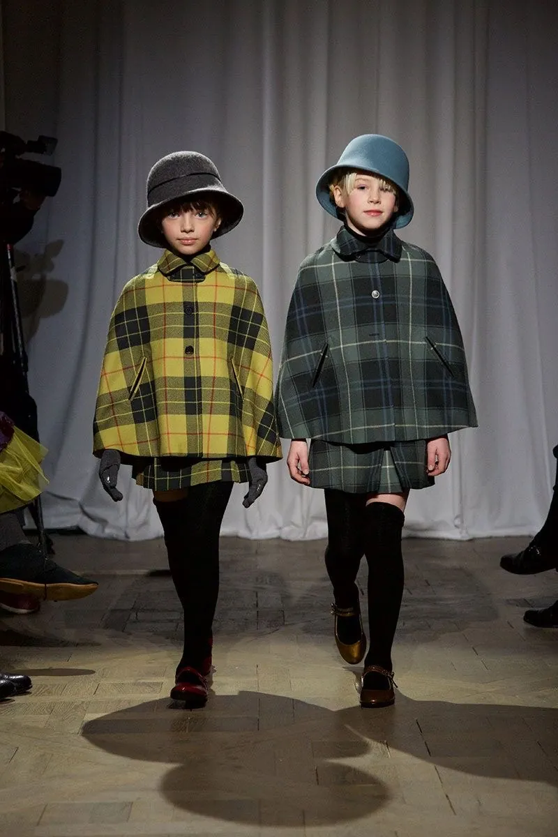 Two children on the runway in checked capes, hats and knee-high socks.